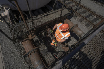 Mitarbeiter DB Cargo beim Kuppeln zweier Güterwagen - Zum Einsatz kommt eine Schraubenkupplung